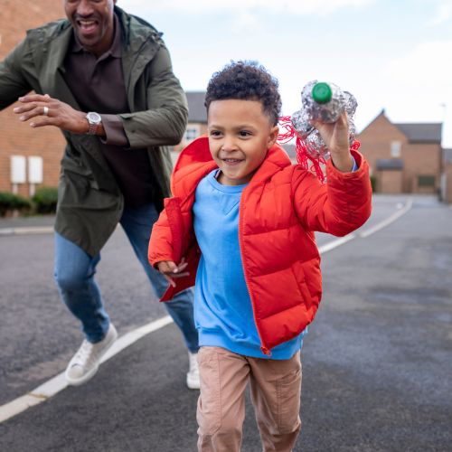Young boy and man running on a pavement